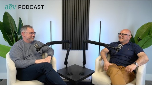 The two aēv podcast hosts seated with microphones